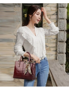 Detail of burgundy crocodile-textured handbag with a leopard print silk scarf decoration