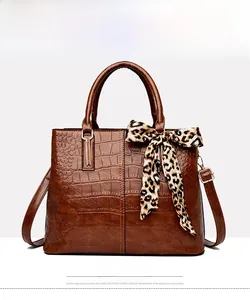 Front view of yellow brown crocodile embossed handbag with leopard print silk scarf detail