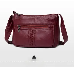 Dettaglio della borsa a tracolla bordeaux con trama litchi e decoro a righe intrecciate