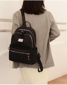 Rear view of a minimalist black oxford backpack worn over a stylish grey-brown blazer