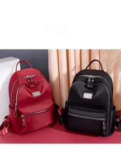 Detail of red and black nylon backpacks with multiple zipper pockets and matte texture