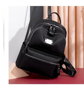Detail view of black oxford nylon backpack with metal hardware and multi-pocket design