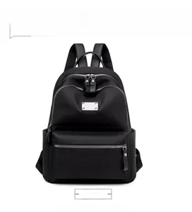 Front view of black waterproof nylon backpack with multiple zipper compartments and metal detail