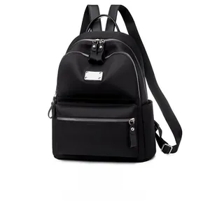 Detail of black nylon backpack featuring multi-layer silver zippers and rectangular logo plaque