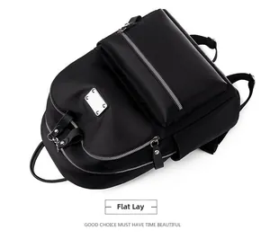 Flat lay detail of black Oxford cloth backpack with layered silver metal zippers and side pockets