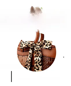 Detail of crocodile pattern texture and leopard print bow on a brown tote bag