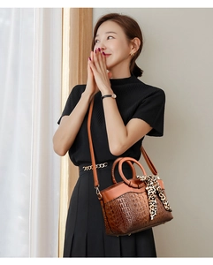 Detail of vintage brown crocodile embossed handbag with golden ring handle and leopard scarf