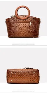 Detail view of the crocodile pattern back and metal protective feet of the brown tote bag
