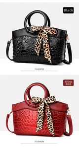 Detail of crocodile pattern bags in black and wine red with leopard silk scarf handles