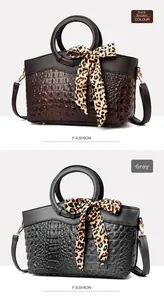 Detail view of crocodile pattern bags in dark brown and grey with leopard print scarves