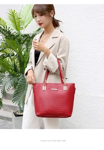 Macro detail of dark red faux crocodile leather tote with elegant golden hardware buckle