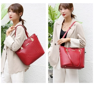 Detail of red crocodile pattern leather tote with gold hardware and logo engraving