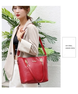 Close-up of red crocodile-embossed tote bag worn by a model in a stylish setting