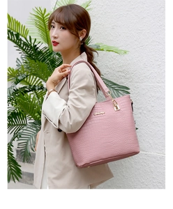 Detail of pink crocodile embossed tote bag with metal chain handle and brand logo