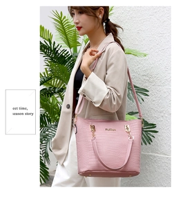 Pink crocodile-embossed large tote bag with gold hardware held by a model outdoors