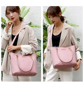 Detail of pink croc-embossed tote bag with gold hardware and protective metal studs