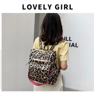 Détail d'un sac à dos léopard avec fermetures éclair et bandoulière tissée colorée