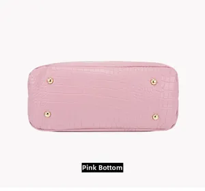 Macro shot of pink crocodile-embossed handbag base with four golden protective metal feet