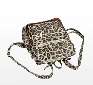 Détail du sac à dos léopard avec zips dorés et accents de sangle tissée géométrique