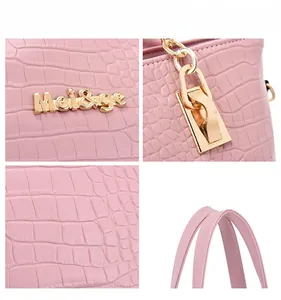 Detail of pink faux crocodile leather texture and gold-tone metal logo on lady handbag