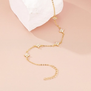 Detailed shot of gold four-leaf clover bracelet with sparkling zircon stones and adjustable chain