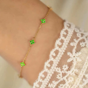 Detailed view of the delicate gold chain bracelet featuring three green clover charms