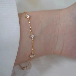 Close-up of gold-plated clover bracelet with sparkling white zircon crystals on a wrist