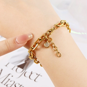 Detail of 18K gold-plated oval link bracelet with a sparkling teardrop zircon charm