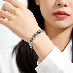 Détail du bracelet gourmette en acier argenté avec plaque de crâne et texture maille