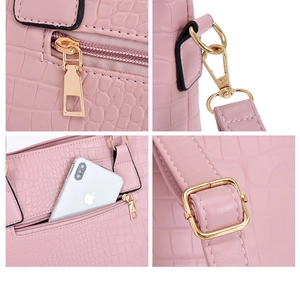 Detail of pink croc-embossed handbag with gold-tone zipper and adjustable strap hook