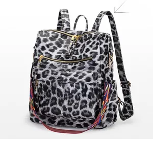 Détail du sac à dos léopard avec fermetures dorées et sangle tissée à motifs colorés