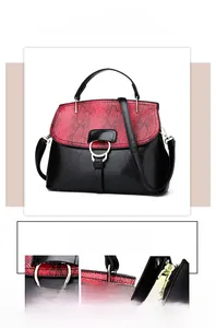 Detail of red python-textured flap and gold metal buckles on a black cross-body bag