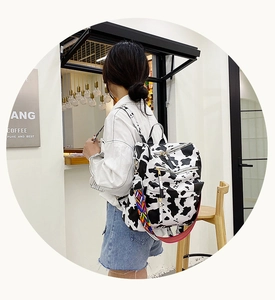 Détail du sac à dos en toile imprimé vache avec bandoulière tissée et poches zippées