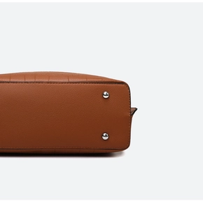 Detail of brown litchi pattern leather bag base with silver protective metal rivets