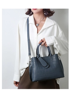 Blue-grey crocodile pattern tote bag shown in a lifestyle setting with a model
