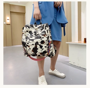 Détail du sac à dos motif vache avec poches zippées et bandoulière tissée colorée