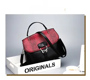 Detail of red and black snakeskin pattern handbag with silver ring clasp on a wooden tray