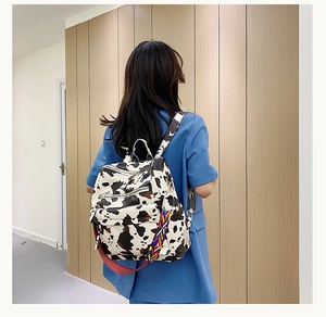Vue arrière d'un sac à dos à motif vache avec des bretelles tissées de style ethnique coloré
