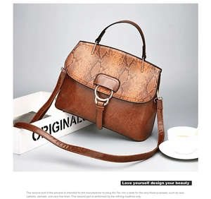 Detail of brown leather handbag with snake pattern flap and gold ring hardware