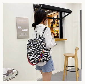 Détail du sac à dos zébré avec sangle imprimée colorée dans un décor de café décontracté