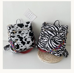 Détail d'un sac à dos imprimé animalier avec bandoulière ethnique colorée sur fond blanc