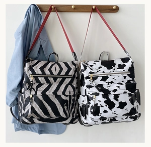Détail de sacs à dos à motifs zèbre et vache avec bretelles rouges et poches