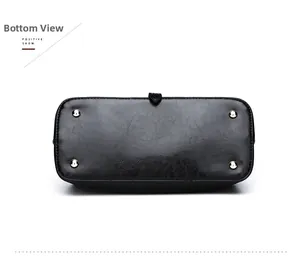 Detailed base of black faux leather bag featuring protective gold metal feet and stitching