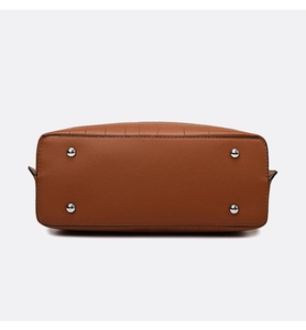 Detail view of brown textured leather bag base with four silver protective metal feet
