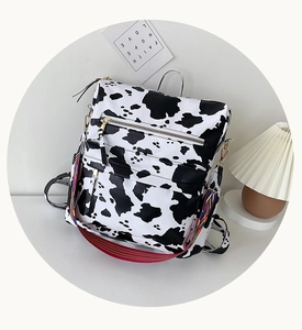 Détail du sac à dos motif vache avec poignée en métal et bandoulière tissée colorée