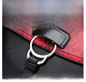 Detail of snake pattern embossed red leather and cat-shaped golden hardware buckle on bag