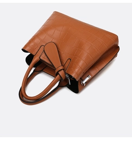 Detail of brown crocodile embossed leather tote bag with stylish knot strap decor
