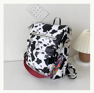 Détail du sac à dos motif vache avec poches zippées et bretelles tissées colorées