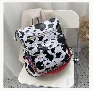 Détail d'un sac à dos motif vache avec fermetures dorées et sangle tissée colorée