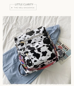 Détail du sac à dos motif vache avec bandoulière brodée ethnique sur tissu blanc